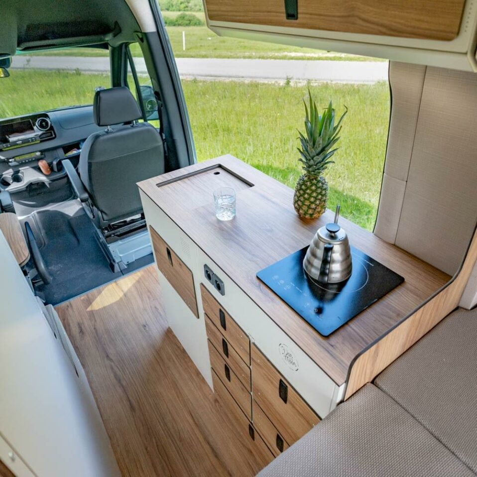 Cuisine Moon Kitchen installée dans un van avec plaque à induction, plan de travail et tiroirs.